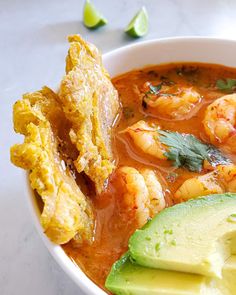 a white bowl filled with shrimp, avocado and tortilla bread sticks