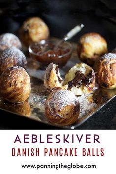 baked pastries on a baking sheet with powdered sugar and chocolate sauce in the background