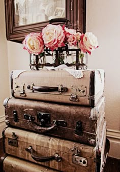 three suitcases stacked on top of each other in front of a mirror and flowers