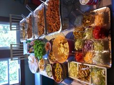 a long table filled with lots of food on top of plates and pans next to each other