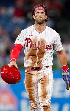 a baseball player holding a red glove and ball in his hand while walking on the field