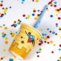 a cup with a straw sticking out of it sitting on top of confetti