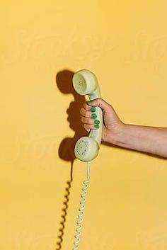 a person holding an old fashioned phone in their hand by jodi lenski for stocksy images