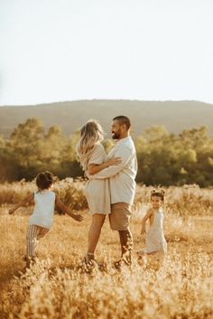 a man and two children are walking through the grass with their arms around each other