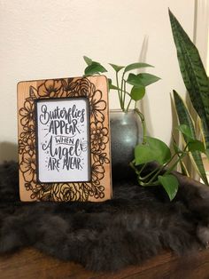 a wooden frame sitting on top of a table next to a potted plant