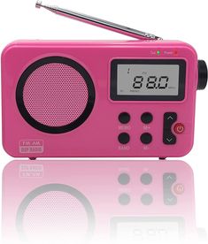 a pink radio with a clock on the front and an antenna attached to it's side