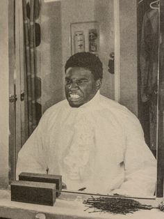 an old black and white photo of a man getting his hair cut in front of a mirror