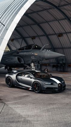 the bugatti is parked in front of an aircraft hangar with another car nearby