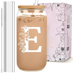 a glass jar filled with liquid next to two straws and a box containing the letter e