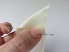 a hand holding a piece of white cloth with the tip of it's thumb