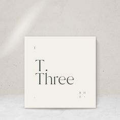 there is a white square with the word three on it in black letters, against a light gray background