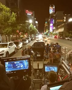 a group of people sitting on the side of a road next to traffic at night