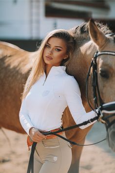 a beautiful woman standing next to a brown horse