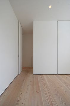 an empty room with white walls and wood floors