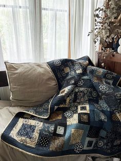 a bed with a quilt on top of it next to two pillows and a window