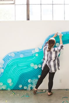 a woman is painting on the wall with bubbles