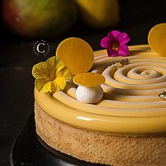 there is a cake with yellow icing and flowers on the top, surrounded by fruit