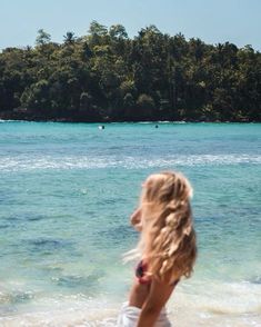 a girl standing on the beach looking out into the water