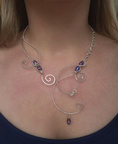 Handcrafted Silver Wire Wrapped Open Collar Necklace, a stunning piece inspired by medieval and Renaissance elegance. Adorned with iridescent purple, blue, and pink shift glass teardrop beads, this elvish torc necklace is perfect for special occasions, cosplay events, or adding a touch of fantasy to your everyday look. The intricate wire wrapping and open collar design ensure a comfortable fit while showcasing its unique craftsmanship. Elevate your style with this exquisite, one-of-a-kind necklace To keep your silver-plated jewelry looking its best, we recommend avoiding contact with harsh chemicals, perfumes, and excessive moisture. Gently wipe it clean with a soft cloth after wearing to preserve its shine and quality. **I use a combination of high quality glass beads, acrylic beads and n Open Collar Necklace, Handmade Adjustable Medieval Necklaces, Adjustable Handmade Medieval Necklaces, Medieval Style Metal Necklaces For Larp, Handmade Fantasy Necklaces For Larp, Silver Elven Jewelry For Festivals, Silver Elven Style Jewelry For Festivals, Torc Necklace, Cosplay Jewelry