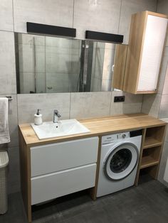 a washer and dryer in a bathroom next to a sink with mirrors on the wall