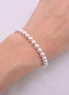 a woman's hand wearing a bracelet with white pearls