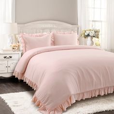 a bed with pink comforter and pillows in a bedroom