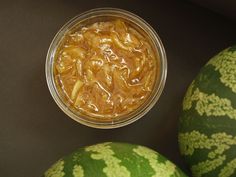 two watermelon halves next to a jar of food on a black table top