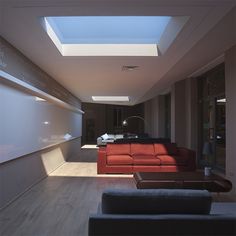 a living room filled with furniture and a skylight in the middle of the room