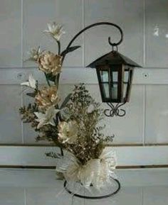 a lamp hanging from the side of a wall next to flowers