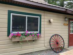 a house with flowers in the window box and a wagon wheel