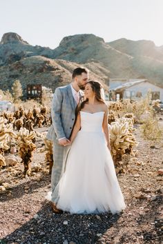 a bride and groom standing in the desert