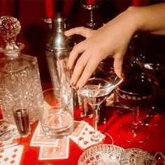 a woman's hand reaching for a glass on top of a red table cloth