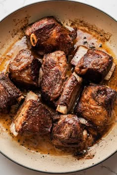 the meat is being cooked in a skillet with brown sauce on top, and it's ready to be eaten