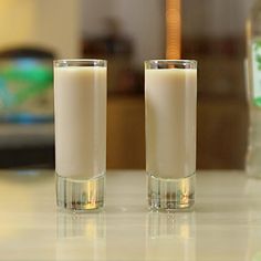 two glasses filled with liquid sitting on top of a counter