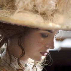 a woman wearing a large hat while looking at her cell phone