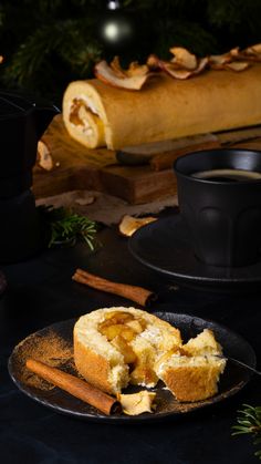 a piece of bread on a plate next to a cup of coffee and cinnamon sticks