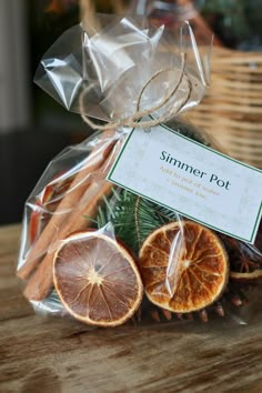 an orange slice and cinnamon stick wrapped in clear cellophane on a wooden table