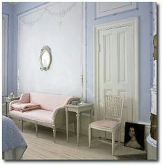 a bedroom with blue walls and white furniture in the corner, along with a pink daybed