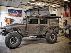 an old jeep with a tent on top in a garage