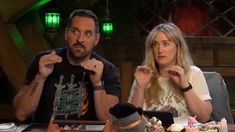 a man and woman sitting at a table with cupcakes