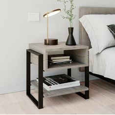 a nightstand with books and a lamp on it in a bedroom next to a bed