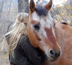 a woman standing next to a brown and white horse