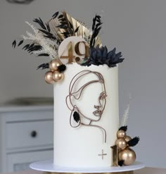 a white cake decorated with gold and black decorations on top of a table next to a clock