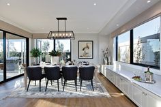 a dining room table with black chairs next to large windows and a rug on the floor