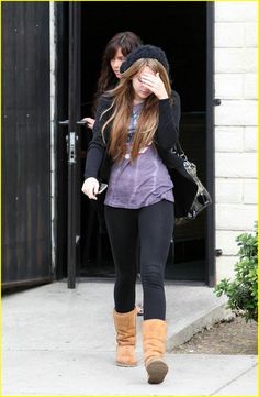 two girls walking down the sidewalk with one holding her head in her hands and another covering her eyes