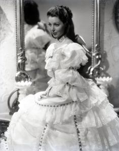 an old photo of a woman in a white dress with ruffles on it