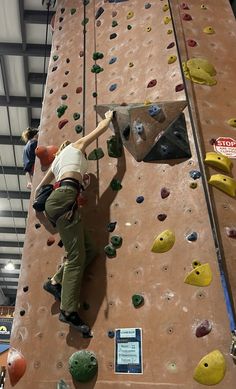 a man climbing up the side of a rock wall in an indoor climbing area with other climbers