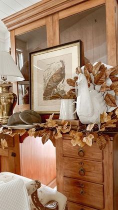 a wooden dresser topped with white vases filled with flowers and leaves on top of it