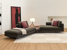 a living room filled with furniture on top of a hard wood floor covered in white and red pillows