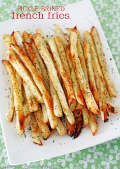 some french fries on a white plate with seasoning sprinkled around the edges